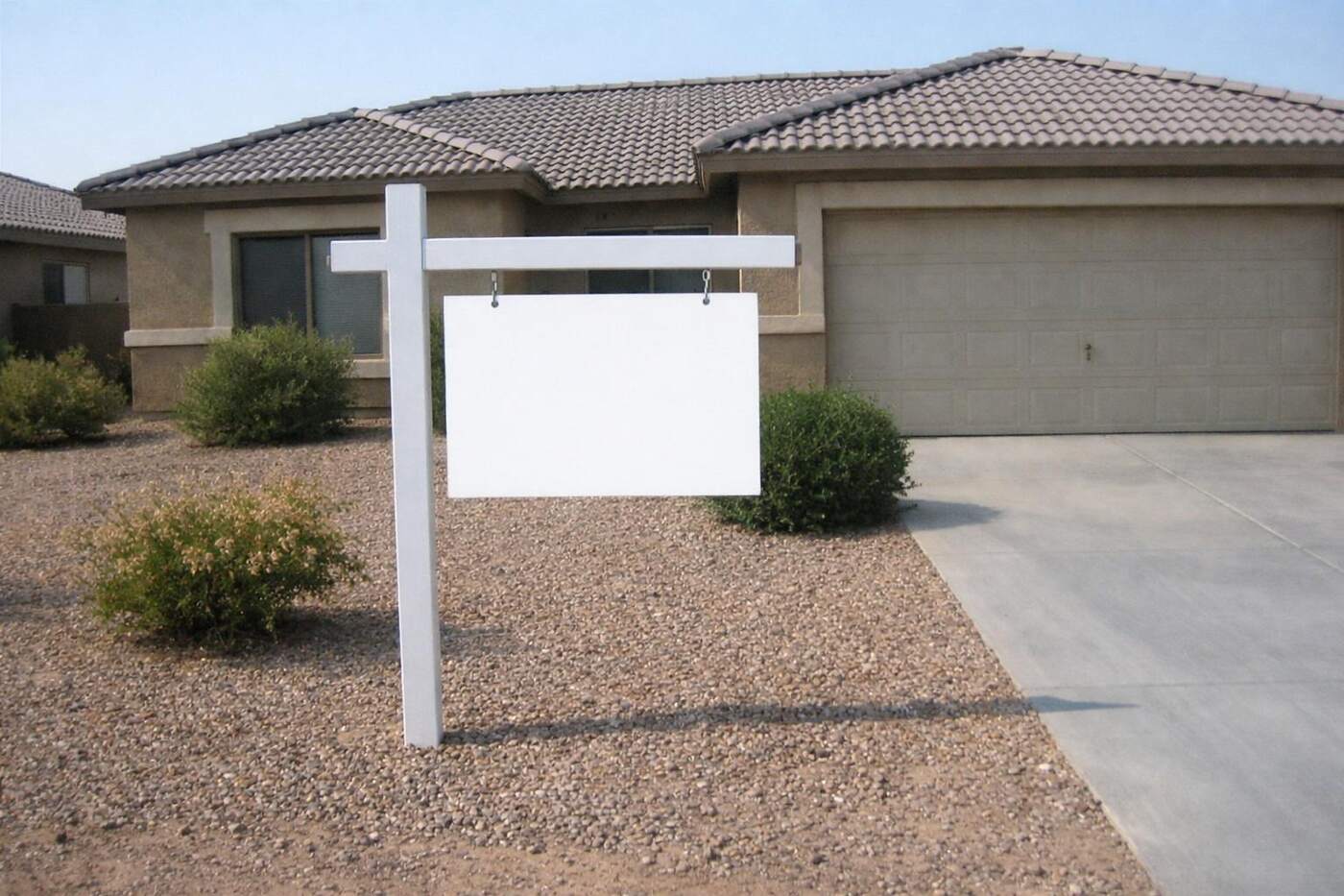 A real estate sign in the gravel front yard of a tile-roofed Phoenix house