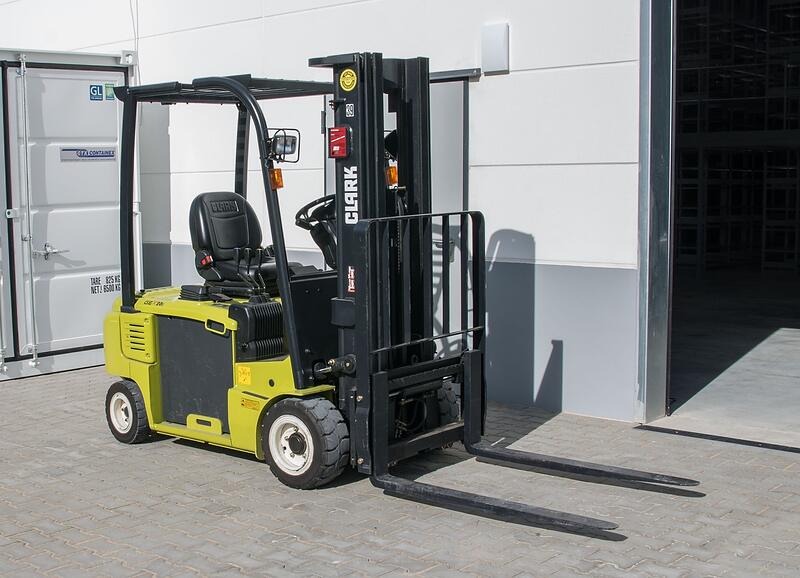 A forklift at the open roll-up door of a warehouse